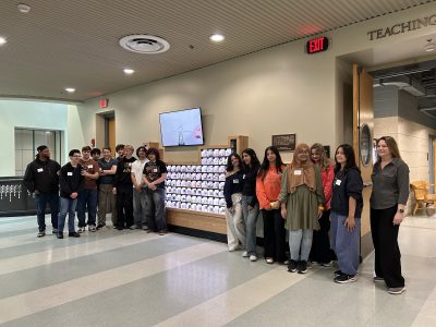 Students standing next to the periodic table in the Chemistry building. 