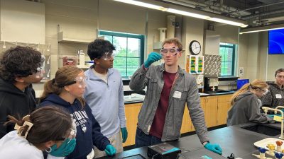 Students observing a chemistry experiment in lab. 